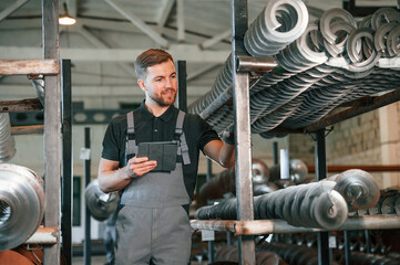 Holding tablet. Man in uniform is in workstation developing details of agriculture technique