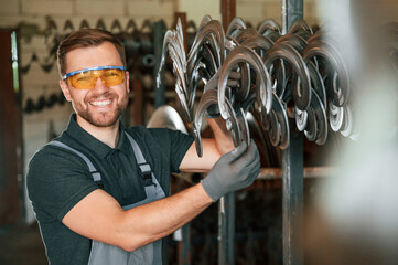 In protective glasses. Man in uniform is in workstation developing details of agriculture technique