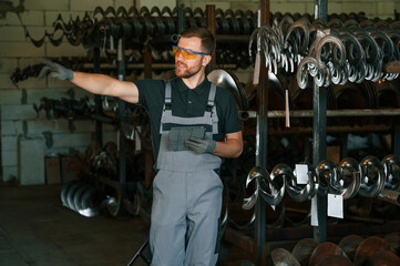 In protective glasses. Man in uniform is in workstation developing details of agriculture technique