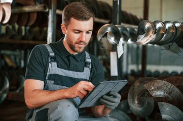 Manager is using digital tablet. Man in uniform is in workstation developing details of agriculture...