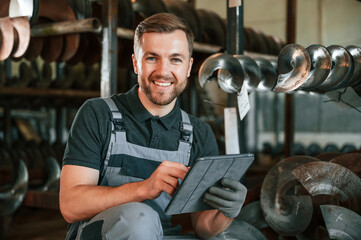 Manager is using digital tablet. Man in uniform is in workstation developing details of agriculture technique