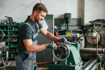 Turning wheel. Man in uniform is in workstation developing details of agriculture technique