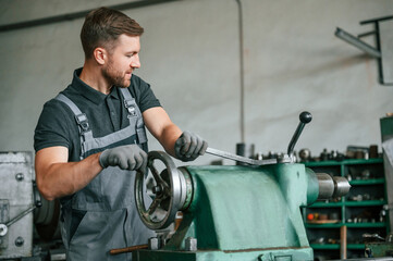 Operating manufacturing equipment. Man in uniform is in workstation developing details of...