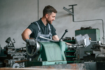 Turning wheel. Man in uniform is in workstation developing details of agriculture technique