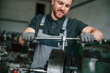 Focused on the developing the parts. Man in uniform is in workstation developing details of...