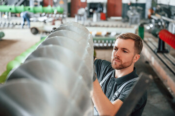 Checking slicing parts. Man in uniform is in workstation developing details of agriculture technique