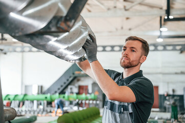 Checking slicing parts. Man in uniform is in workstation developing details of agriculture technique