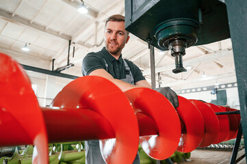 Attention to detail. Man in uniform is in workstation developing parts of agriculture technique
