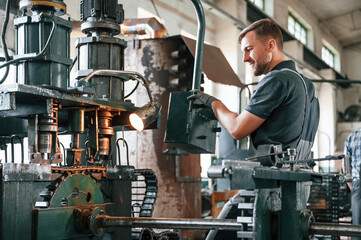 Metal processing device. Man in uniform is in workstation developing details of agriculture technique