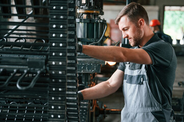 Metal processing device. Man in uniform is in workstation developing details of agriculture...