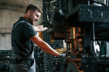 Metal processing device. Man in uniform is in workstation developing details of agriculture technique