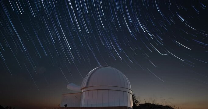 Timelapse of an astronomical observatory under star trails sky at night