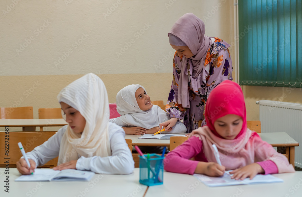 Canvas Prints female hijab muslim teacher helps school children to finish the lesson in the classroom.