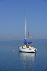 Albania, May 12, 2022 - Sail boat and reflection anchored near shore.