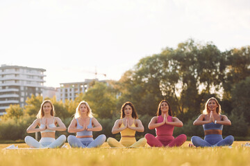 It lotus pose. Group of women have fitness outdoors on the field together
