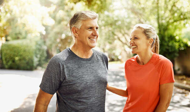 Happy mature couple keeping active, fit and healthy while jogging, running or going for walk outdoors in nature environment. Laughing senior man and woman enjoying a break from workout or exercising