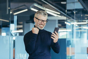 Successful and satisfied senior businessman celebrating victory gray haired man in glasses working...