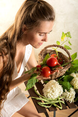 Frau mit frischen roten Tomaten in  den Händen sitzt am Tisch und betrachtet Ihre Ernte.