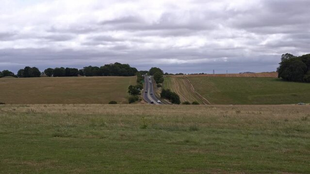 Scenic rural landscape wit road passing famous World Heritage Site Stonehenge on a cloudy summer day. Movie shot August 2nd, 2022, Stonehenge, England.