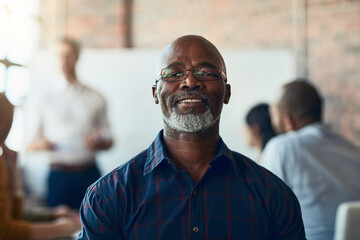 Mature business man sitting in a meeting, conference or seminar in a boardroom with colleagues at work. Closeup portrait of face of a senior, happy and corporate professional in a training workshop