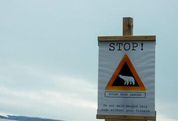 Attention, polar bear. Warning sign against gray sky. Seen in Ny-Alesund, Svalbard, Norway. Place...