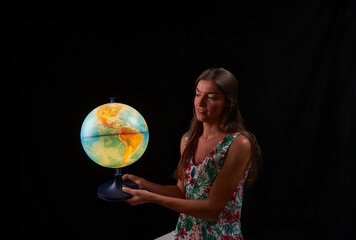 Fototapeta premium young woman observes the sphere of the world illuminated from within