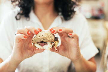 Woman holding a traditional Portuguese meat sandwich called "prego" with a steak and mountain cheese