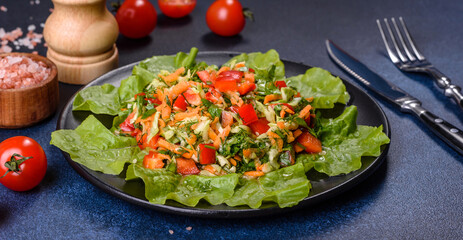 Plate of salad with vegetables and greens on a dark concrete table