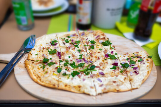 Flammkuchen auf Holzbrett rustikal angerichtet serviert