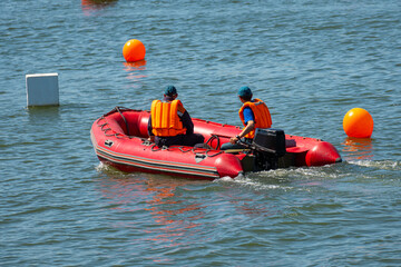 rescuers on a red inflatable boat patrol sea.