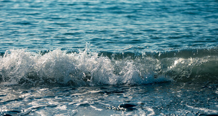 Clean Surf With Splashes Of Foam On A Pebble Beach. Sunny Day. Selective Focus. Short Exposure.