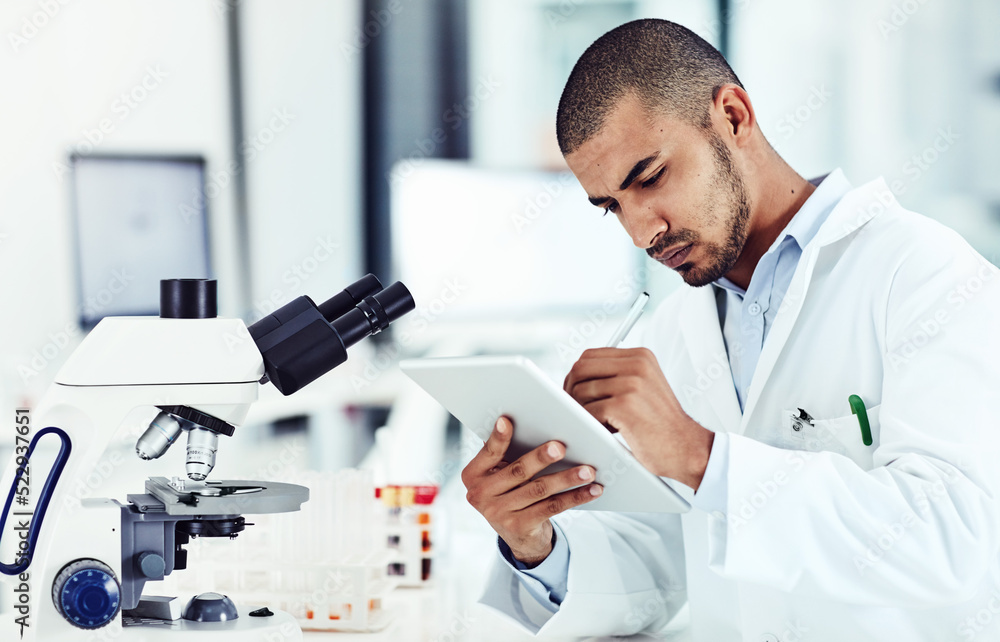 Poster serious male scientist working on a tablet reviewing an online phd publication in a lab. laboratory 