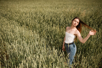 Naklejka na ściany i meble Beautiful girl posing in wheat field. Emotions of a girl