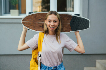 teenager with skateboard standing in front of her house © cherryandbees