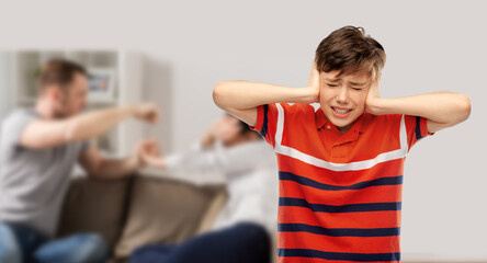 domestic violence, abuse and family issue concept - boy closing ears with hands over parents...