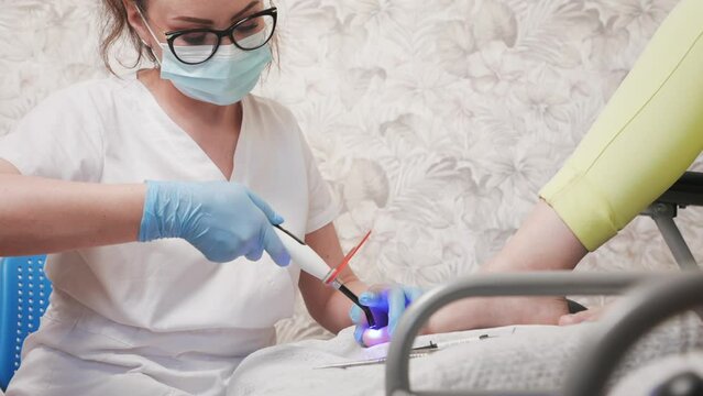 Portrait of professional orthopedist installs a titanium thread on the big toe. Correction of ingrown toenail. The concept of podology, orthopedics and chiropody.