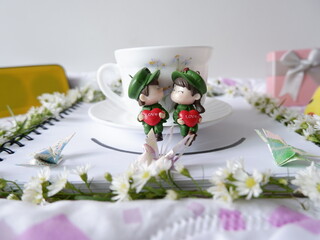Sweet and beautiful white atmosphere in the room decorated with a white coffee cup with a couple dolls and lovely flowers.