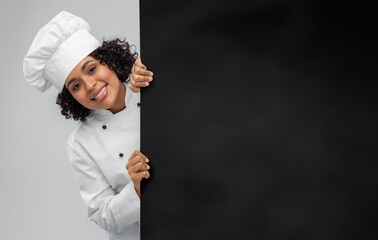 cooking, advertisement and people concept - happy smiling female chef in toque with empty black board over grey background