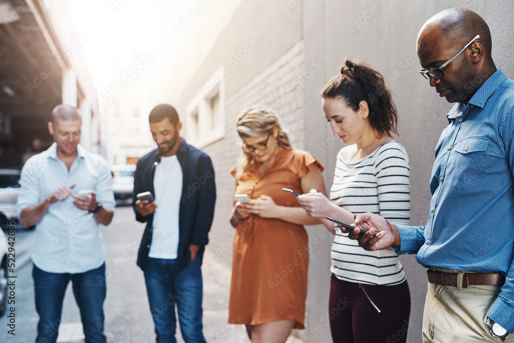Aufkleber Business people reading text on phone, checking notifications and typing messages online during a break at work. Group of diverse colleagues scrolling on the internet, browsing app and networking