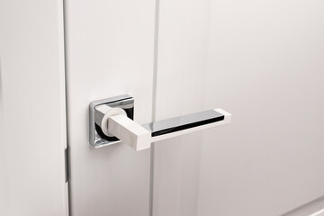 Door handle on white closed doors in modern loft style in interior.