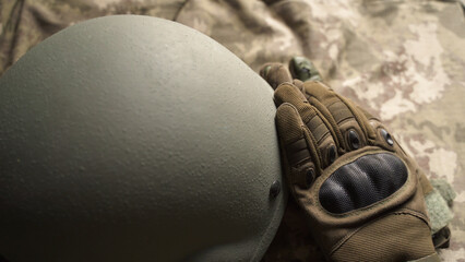 tactical gloves and helmet on the table. protective soldier's equipment. infantry head protection. storage of military items. providing the troops with the necessary protection in war - obrazy, fototapety, plakaty