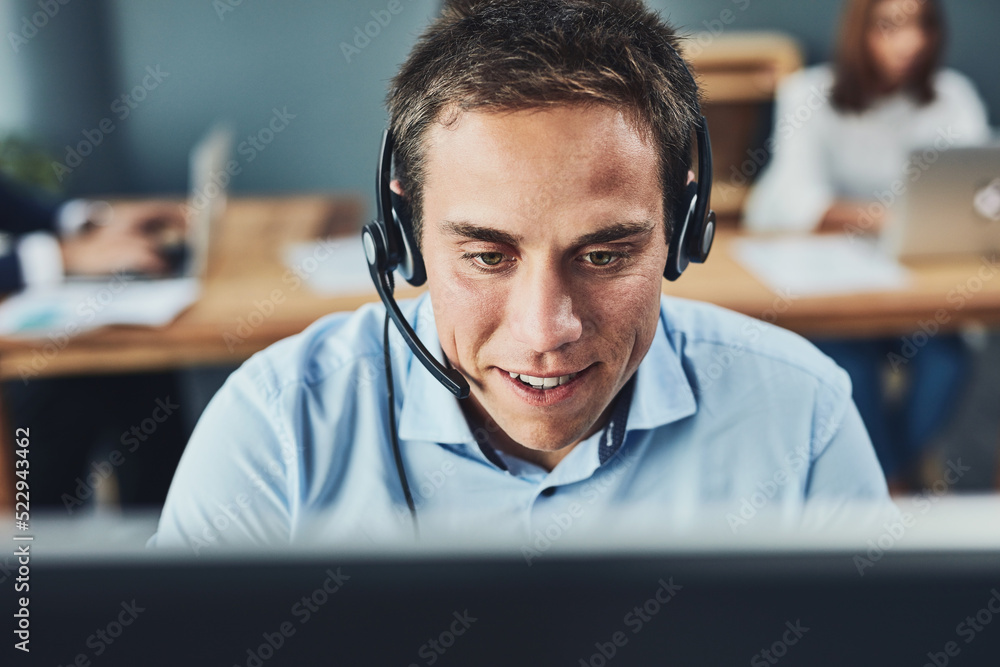 Poster closeup of a young male call center agent consulting and giving support while working in a busy offi