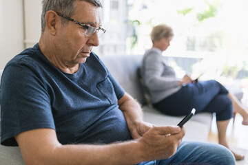 Senior couple using their mobile phones at home