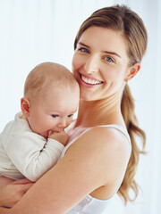 Mother bonding with baby boy, smiling and enjoying family time in a room at home. Portrait of a happy, loving and caring single parent holding or carrying an adorable, cute and little newborn child