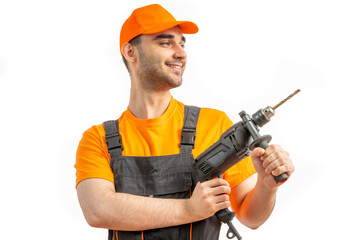 Young worker drilling with electric drill in his hands. Tool for boring holes. Craftsman repairman wearing orange uniform cap and t-shirt, overalls on a white isolated background for advertising