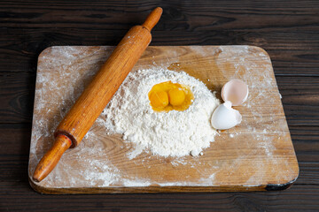 Making homemade dough for bread, pastry, and cookie. Wood rolling pin, flour, eggs. Rural food cooking. Top view