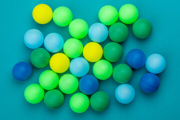Abstract colored balls background. Multi-colored taw toy scattered on bright paper. Base for design nice backdrop, wallpaper, poster. Noisy surface texture