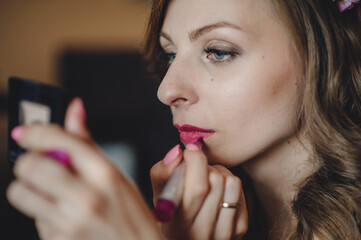 The girl makes the perfect makeup on the face and skin. The stylist draws lips with a lipstick. Beautiful brunette woman. Close-up.