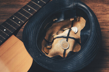 The concept of a street musician beggar. Hat with coins and a guitar. View from above.