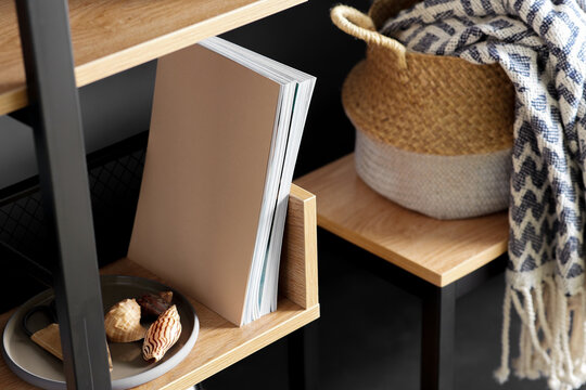 interior and home decor concept - close up of book shelf with art and decorations over black background
